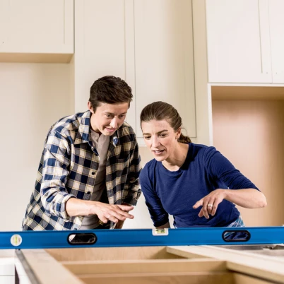 Man works on a laptop at the kitchen table beside a child, reflecting everyday home life and the financial goals home loans can help support.