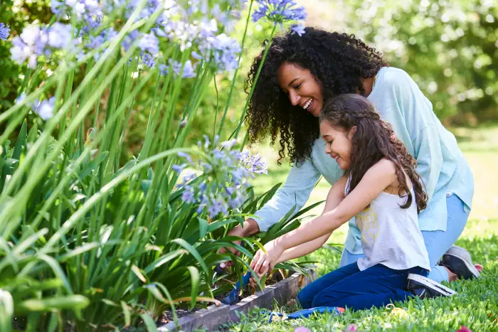 Mother and daugther outside smiling and gardening.