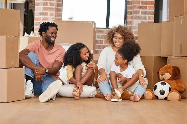 A family gathers on the floor with boxes around them.