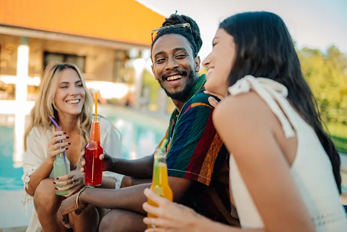 Photo of three friends socializing poolside