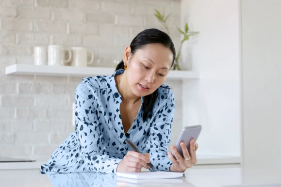 A woman checking on rates on her phone in her modern kitchen. 