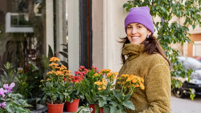 Woman in coat with flowering plants.