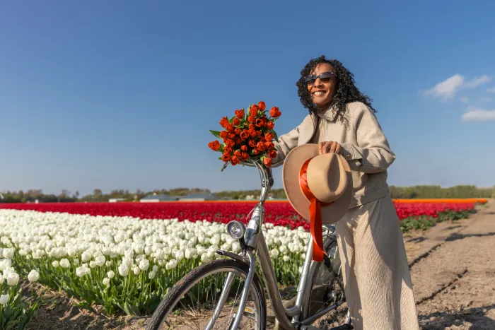 Woman with bike in front of flowers.