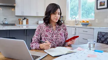 A woman sitting at the kitchen table working on her computer