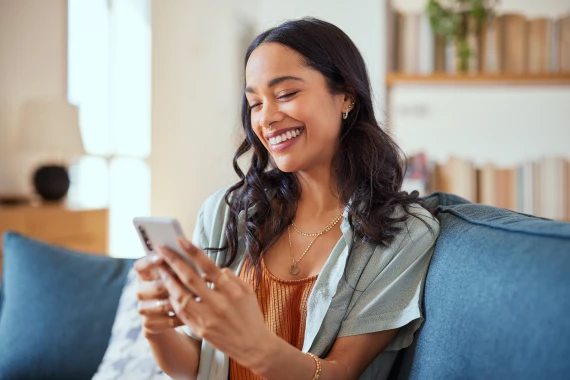 A woman on a couch, using her phone, embodying a casual and relaxed home setting.