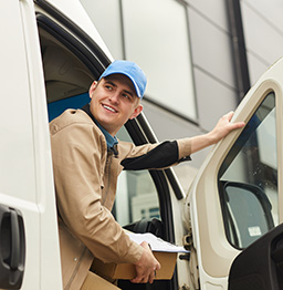 Delivery driver looking out van door.