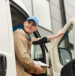 Delivery driver looking out van door.