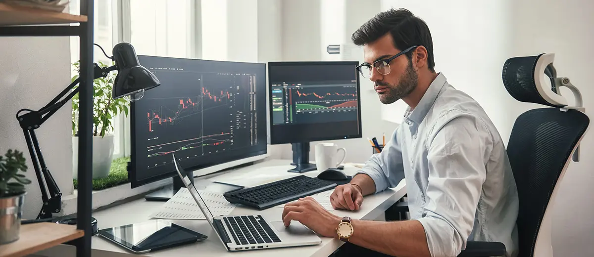 Man at desk looking at stock charts on his computer.