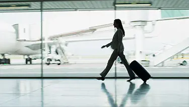 A business traveler walking through airport while pulling luggage