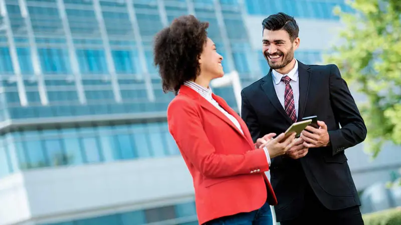 Professional man and woman standing outside a commercial building discussing CRE trends