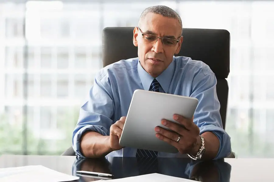 Man wearing a looking at treasury exchange rates on a tablet.