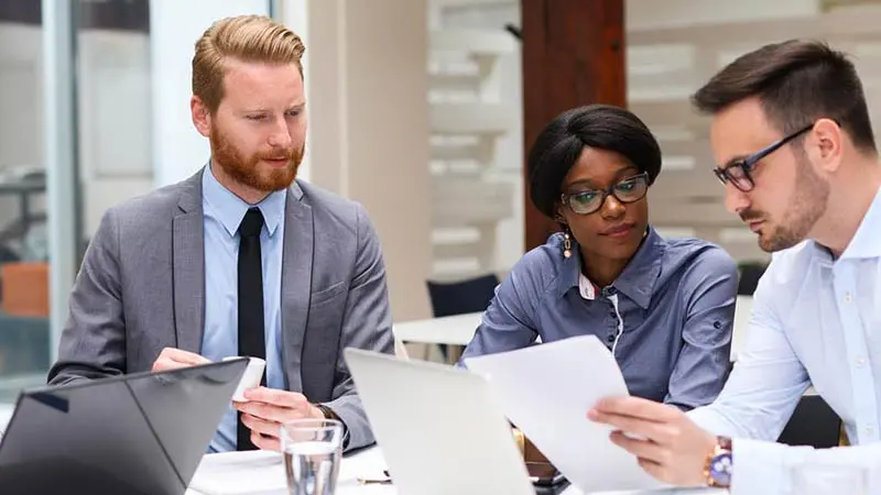 Three professional individuals looking at documents