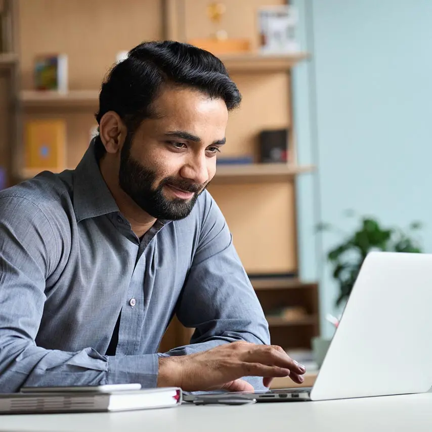 Man at a desk browsing the internet on a laptop