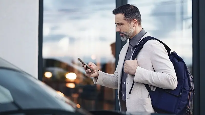 Man using a laptop in an airport to assess p-cards vs corporate cards