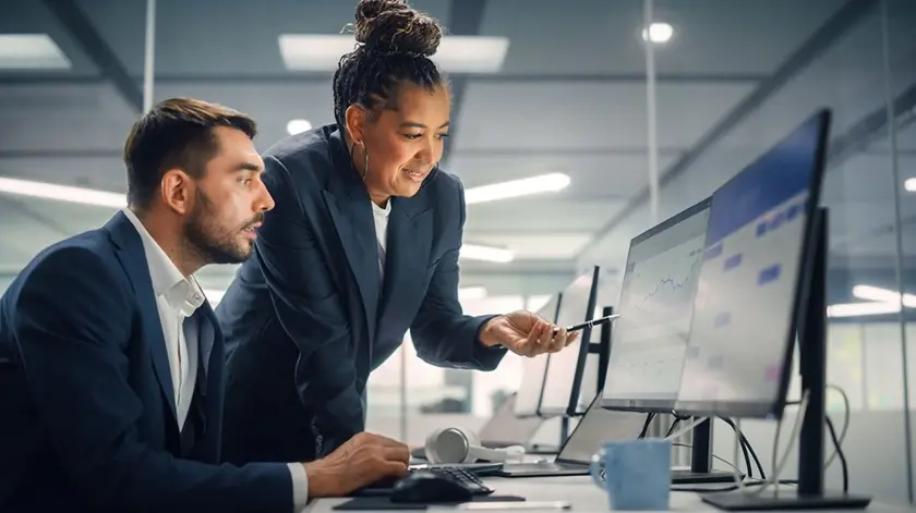 Two business colleagues looking at charts on a computer screen