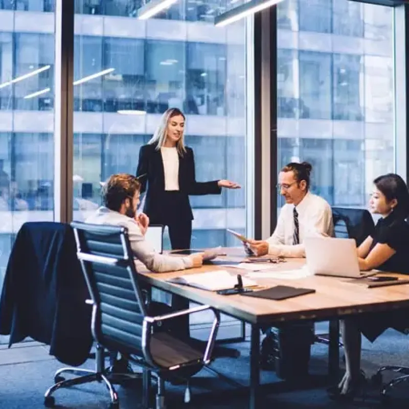 Four colleagues in a large glass boardroom, sitting at the table and discussing FX