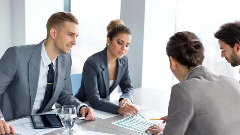 Four colleagues in suits looking at charts about exchange traded products