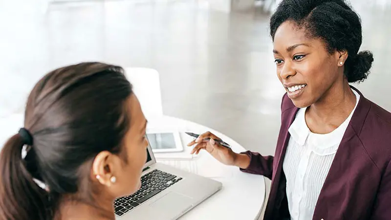 Two women discussing business in front of a laptop