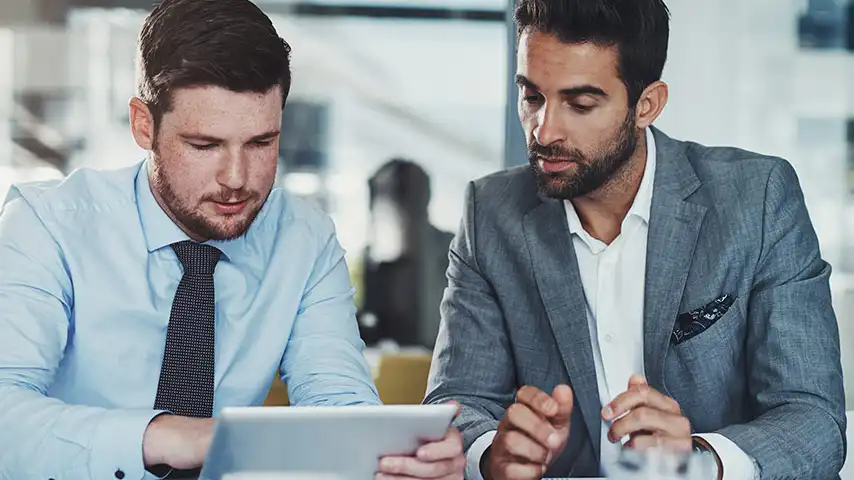 Two business men with a tablet, digitizing account protection.