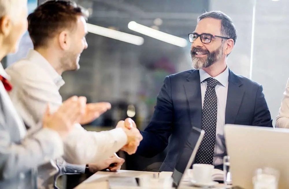 Three colleagues in a meeting discussing leasing or buying equipment