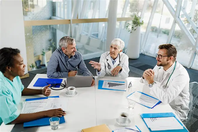 Group of four healthcare professionals sitting and talking about revenue cycle management healthcare
