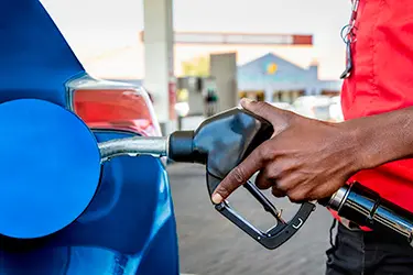 Man holding a fuel pump dispenser while fueling a car.