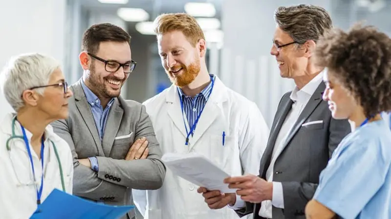 Three doctors talking to two business professionals