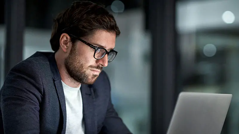 Man wearing glasses working on laptop 
