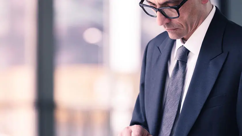 Middle aged professional man in a suit standing in front of a window in his office