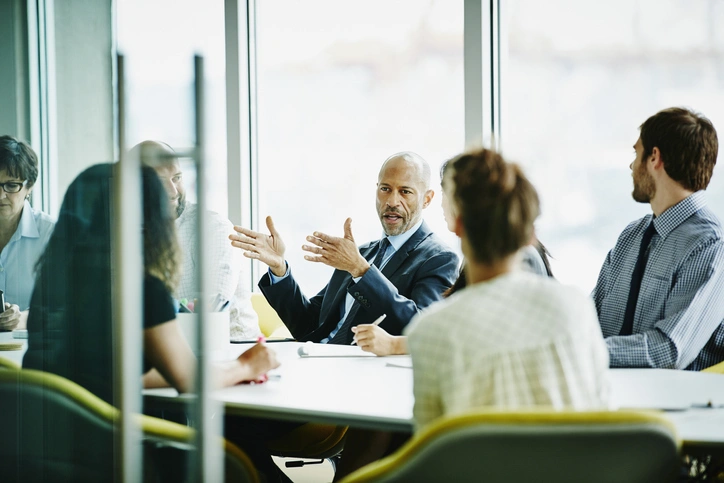 Businessman in conference room speaks to his colleagues about high-yield bond and loan markets.