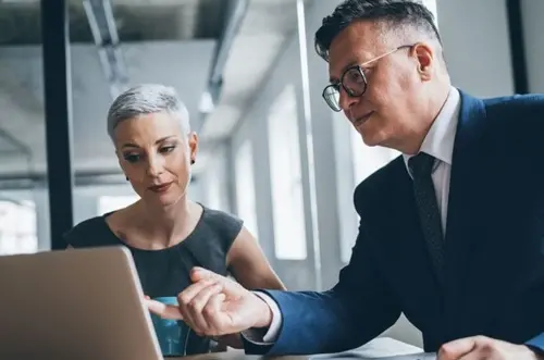 Two professional colleagues looking at a laptop in their office