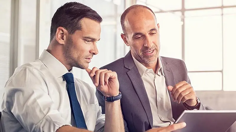 Two professional men sitting and looking at CLO options on a tablet device