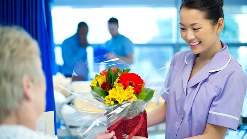 Nurse in a hospital giving flowers to a patient and talking about healthcare payments