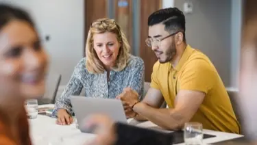 Photo of people looking at laptop on table.