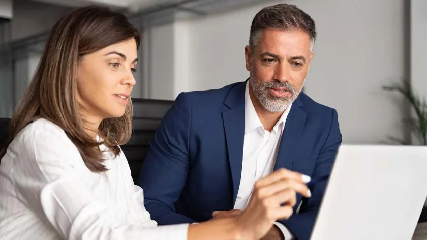 Man and woman looking at laptop while discussing embedded finance for B2B payments