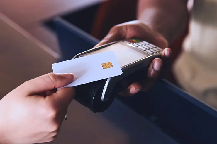 Closeup of a hand holding a credit card and tapping to pay