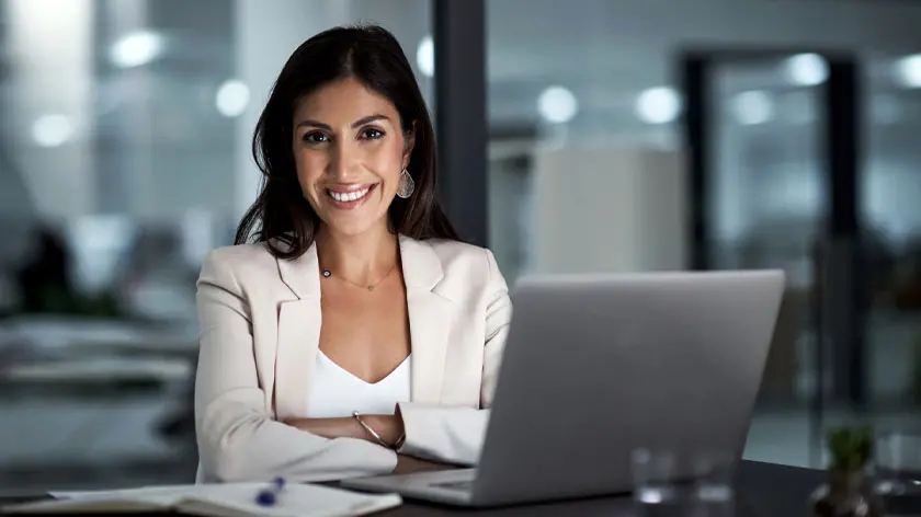 Woman sitting at a laptop smiling while looking for warehouse lenders