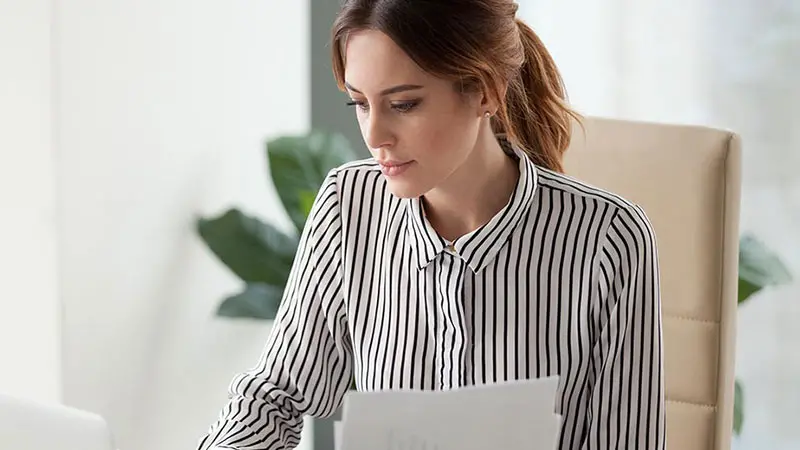 Woman wearing a striped shirt reading paperwork about investment structures.