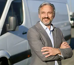 Business man leaning against a fleet truck. 