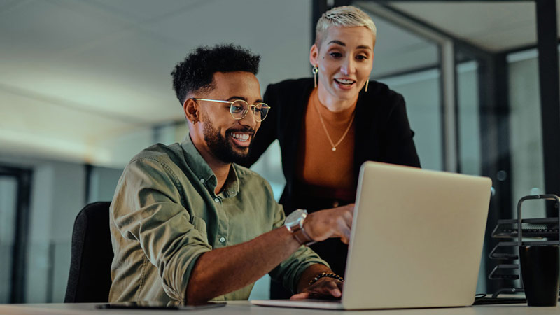 Man and woman smiling and looking at a computer screen together