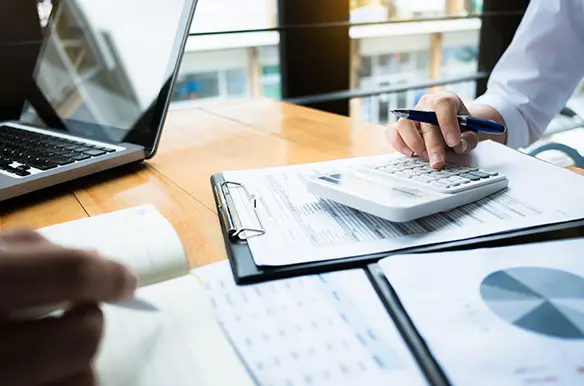Two young professionals, one male and one female, who are looking at a computer monitor together as they discuss the order to cash cycle