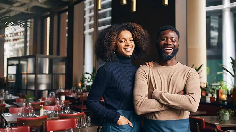 Young business owners standing in a restaurant and smiling