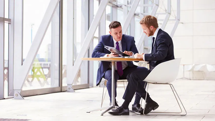 Two men sitting at desk looking over KYC and AML requirements