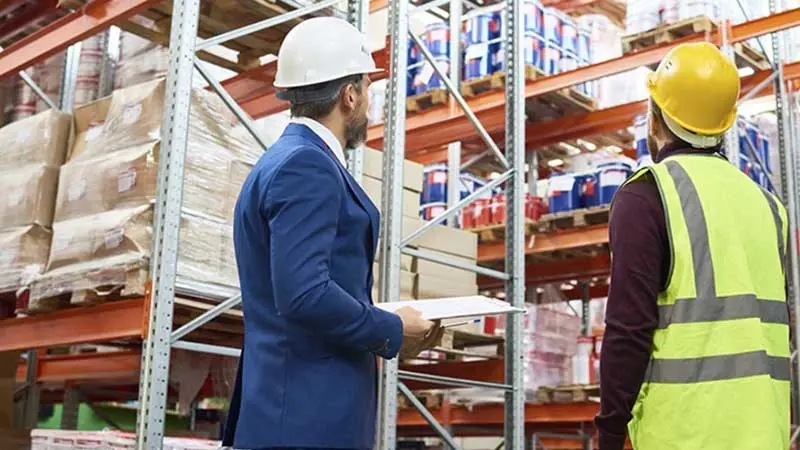 Two construction workers wearing hard hats in a warehouse