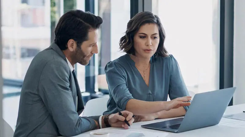 A businessman and a businesswoman sit in front of a laptop computer exploring U.S. Bank institutional and investment services.