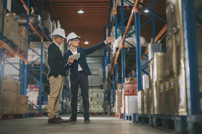 Businessmen in warehouse discussing shipping and supply chain risk