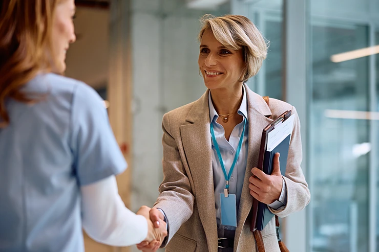 Hospital administrator shakes hands with a nurse and discusses consolidating payments in healthcare EHR systems.
