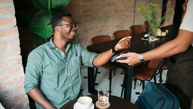 Man in a café using his watch to make a payment.
