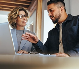 Man and woman reviewing data on a laptop.