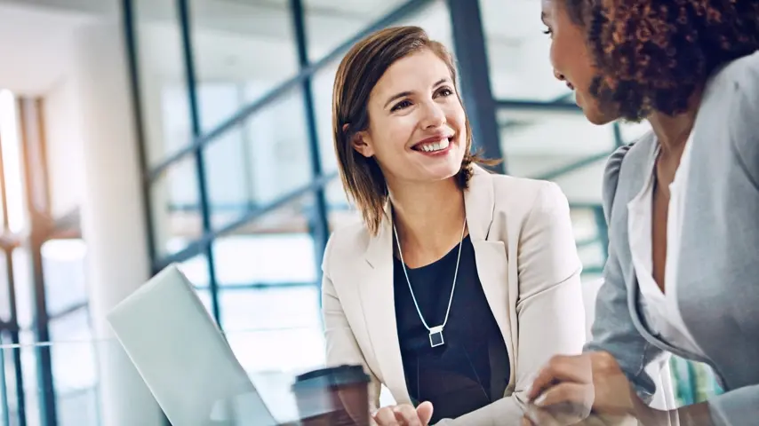 Two people sitting at a desk talking to each other